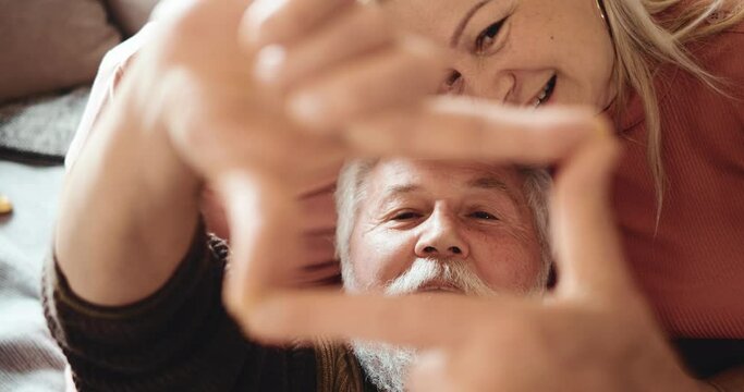 Happy old adult man grandmother and cute adorable small kid granddaughter make shape hand gesture. Improvised camera for family selfies