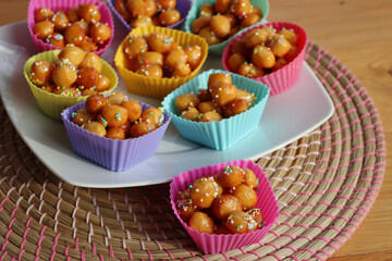 Traditional italian fried Struffoli with honey and sugar sprinkles  on a plate on wooden table