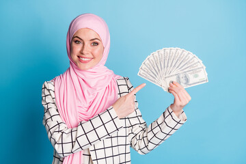 Portrait of pretty cheerful rich muslimah girl holding in hands demonstrating finance isolated over...