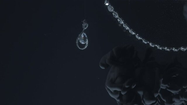 Set of diamond earrings and pendant moving on black background