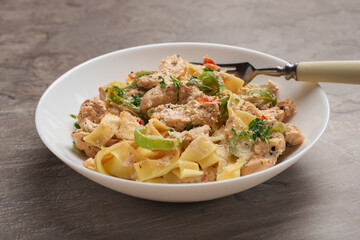 Close Up cajun chicken Fettuccine pasta in a creamy sauce on white plate on dark stone table. American cuisine.