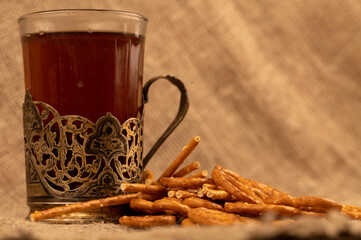 Salted breadsticks and salted pretzels in bulk and a glass of tea in a cup holder on the table.