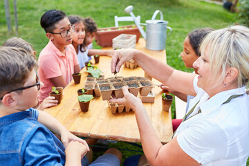 Lehrerin zeigt Kindern die Aussaat von Pflanzen