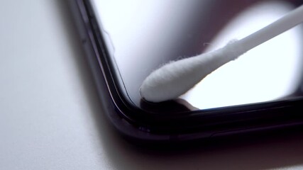 Hand with a cotton swab to clean the smartphone camera - Powered by Adobe