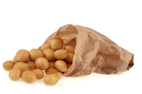 Sac en papier de pommes de terre grenaille renvers&eacute; en gros plan sur fond blanc