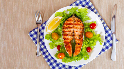 Grilled salmon steak put on green vegetable taken from top view.
