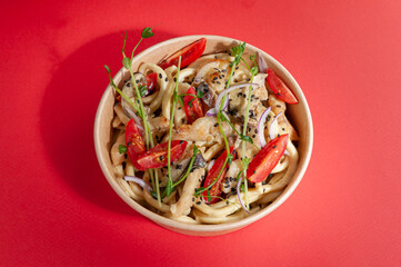 Wok with egg noodles and chicken in a creamy curry sauce. In a food delivery plate. Close-up. view from above. Isolated.