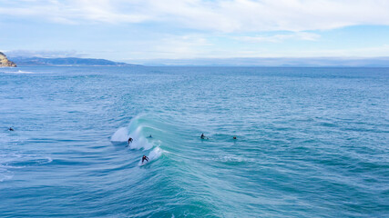 Naklejka premium Aerial drone view of surfers riding perfect swell waves in the beach of Los Caños de Meca in Cadiz, South Spain