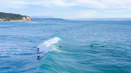 Aerial drone view of surfers riding perfect swell waves in the beach of Los Caños de Meca in...