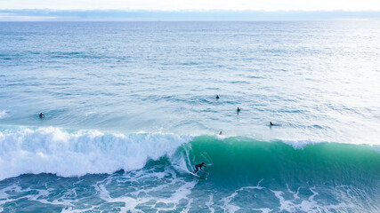 Aerial drone view of surfers riding perfect swell waves in the beach of Los Caños de Meca in Cadiz, South Spain