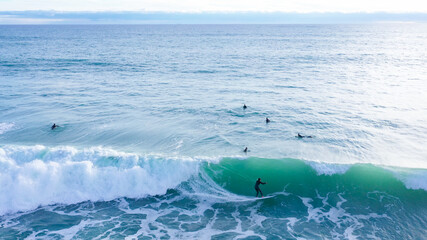 Aerial drone view of SUP surfer riding perfect Atlantic waves in the south coast of Spain doing...