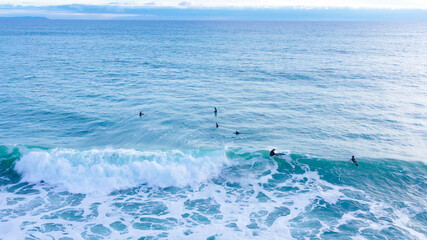Naklejka premium Aerial drone view of surfers riding perfect Atlantic waves in the south coast of Spain, Caños de Meca near Trafalgar