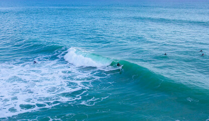 Naklejka premium Aerial drone view of surfers riding perfect Atlantic waves in the south coast of Spain, Caños de Meca near Trafalgar