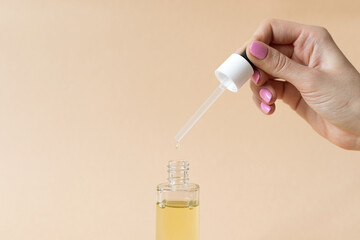 Female hand holding bottle with cosmetic argan oil, skin care concept