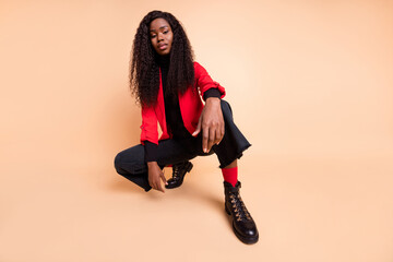 Low angle view full body photo of afro american stunning lady sit wear boots red blazer isolated on...