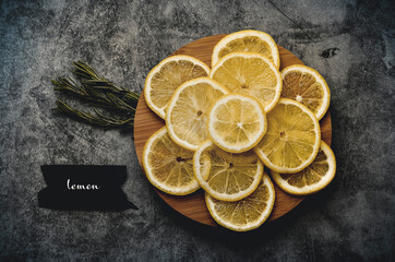 lemon slices on a round wooden board, black paper with the inscription lemon in English on the left...