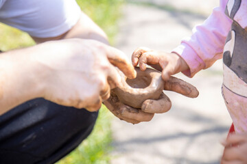 dad and toddler make clay outside on a sunny day close-up, no face