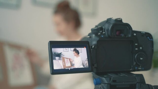 Camera recording a video tutorial. Close-up. Streamer at home. Young female artist explaining her illustration.