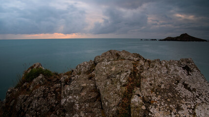 Mer et rochers en pose longue sous un ciel nuageux