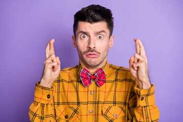 Photo of young man nervous worried crossed fingers hope wish luck fortune isolated over violet...