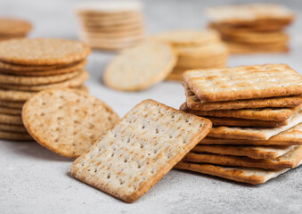Fototapeta na wymiar Stack of various organic crispy wheat, rye and corn flatbread crackers with sesame and salt on light kitchen table background