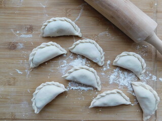 Fototapeta na wymiar Raw dumplings on a wooden board. The process of making dumplings.