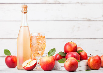 Bottle and glass of homemade organic apple cider with fresh apples in box on wooden background