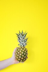 Man holding pineapple against yellow background