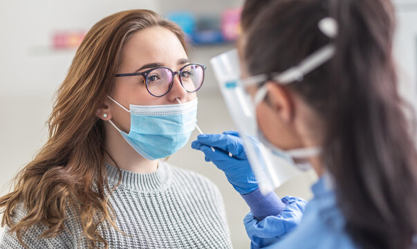 Female patient wearing mask over mouth is having sample taken from nose for a pcr test for Covid 19