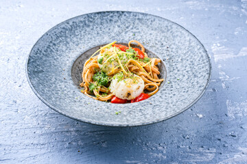 Modern design traditional fried scallops with tomatoes, broccoli pesto and Italian spaghetti pasta served as close-up on a Nordic design plate with copy space