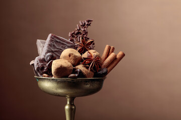 Various chocolates with ingredients in an old brass bowl.
