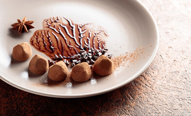 Chocolate truffles on a beige plate with chocolate sauce.