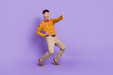 Full length photo of sweet funky young man wear plaid shirt bow tie dancing empty space isolated violet color background