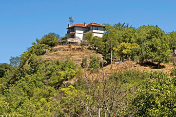 View of the beautiful village of Nisovo, Bulgaria, located below, above and in the high limestone cliffs, protected by magnificent deciduous trees 