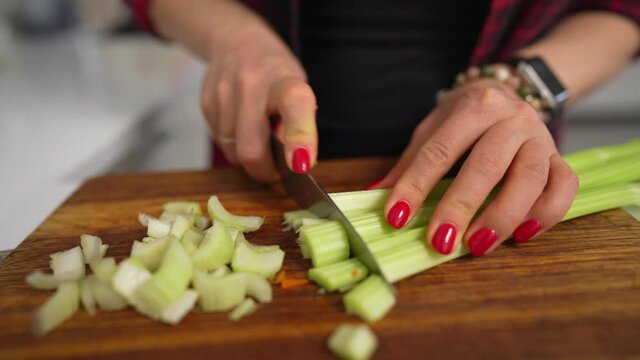 woman cuts celery on a cutting Board for cooking homemade vegetable salad. High quality 4k footage