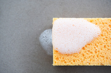 Close up of yellow scouring sponge on the kitchen counter top with soap scum