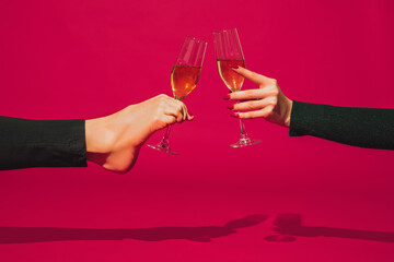 Clinking glasses. Bright fashionable hand and leg working up daily things together. Modern artwork, contemporary art. Trendy colors, magazine style. Usual routine in unusual way. Pink background.