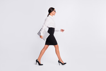 Full size profile photo of optimistic brunette hairdo lady hold laptop go wear spectacles shirt isolated on grey color background