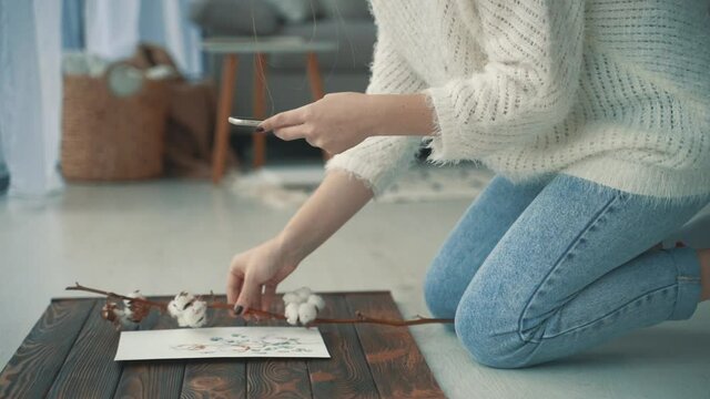 Young female creator taking photos of her illustrations. Streamer at home.