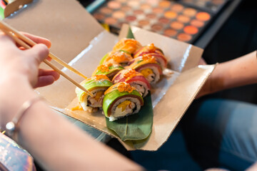 close up of chopsticks taking portion of sushi roll on the table restaurant. eating sushi roll using chopsticks