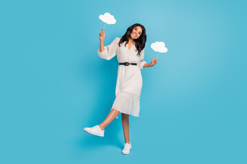 Full length body size view of attractive cheerful girl holding in hands two clouds having fun isolated over bright blue color background