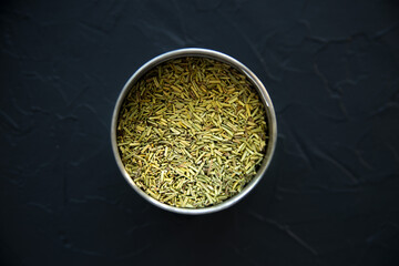Dried rosemary spice in a metal box on a black background