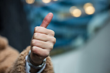 Woman on street  with thumb up. Close up.