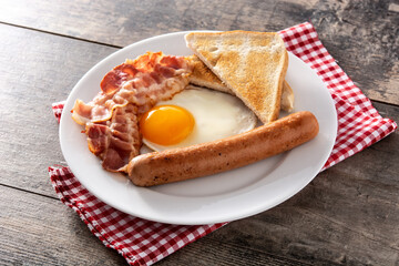 Traditional American breakfast with fried egg,toast,bacon and sausage on wooden table