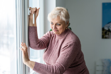 Portrait of senior woman standing at the window at her home