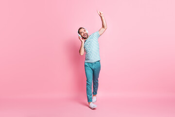 Full length body size view of nice cheerful guy walking enjoying listening melody having fun rest isolated over pink color background © deagreez