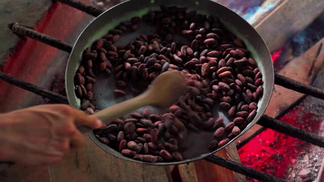 Person Roasts Coffee Beans In Pan With A Wooden Spoon Over A Wood Fire