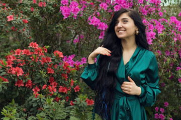 Happy girl smiling in blooming garden, beautiful garden of pink flowers