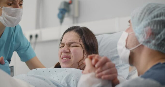 Close up of young woman giving birth in hospital delivery book