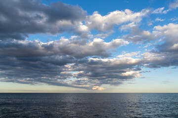 landscape of calm dark blue ocean water under an expressive sky with clouds